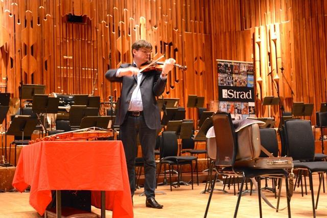 A violinist participating in a blind test, wearing headphones and a blindfold to eliminate visual and auditory bias