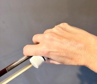 The bottle held in the palm while the fingers hold the bow. The tilt of pronation is visible: the weight pours toward the string.